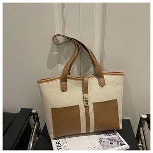 Detailed close-up of retro canvas tote bag with brown leather pockets and metal lock