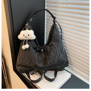 Dettaglio della borsa Hobo nera plissettata con un grazioso ciondolo a nuvola di peluche