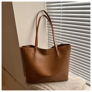 Dettaglio di borsa tote in pelle marrone caramello liscia con sottili spalline per ufficio