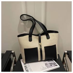 Detailed close-up of large exterior pockets and metal clasp on the color-block tote bag