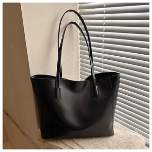 Dettaglio della borsa tote in pelle nera con cuciture rifinite e sottili tracolle moda