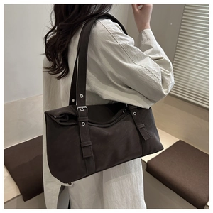 Detail view of a large vintage coffee brown shoulder bag with silver buckle and rivets
