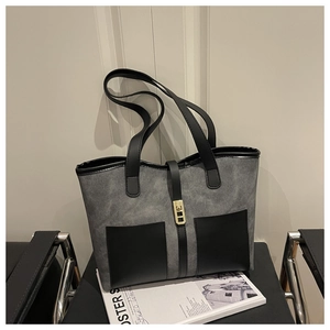 Close-up of dual front pockets and gold buckle on a grey and black tote bag