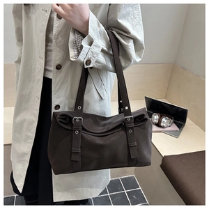Detail of dark brown faux suede tote bag featuring metallic buckle and dual handles