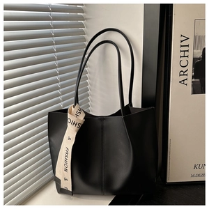 Close-up of black leather tote bag with fashion ribbon and artistic shadow detail
