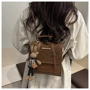 Detailed view of leopard print flap and gold trim on a brown faux leather backpack