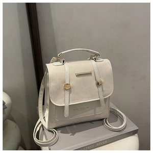 Detail of creamy white PU leather backpack with gold metal hardware and flap closure