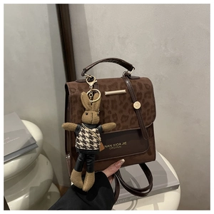 Detail view of brown leopard print flap handbag featuring a knitted rabbit bag charm