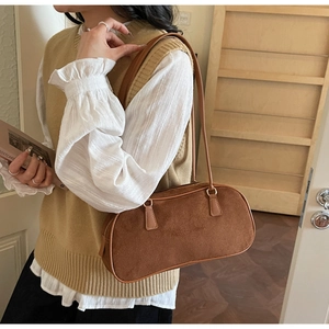 Detailed close-up of brown suede shoulder bag featuring a sleek zipper and slim handle