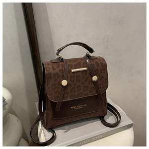 Close-up of leopard print handbag with brown leather trim and gold metal closure