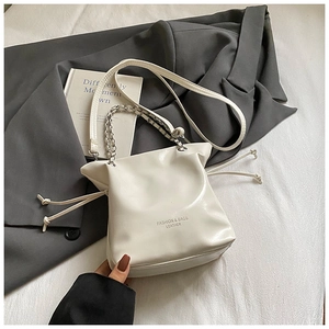 Détail du sac seau en cuir blanc montrant le cordon de serrage et la chaîne argentée