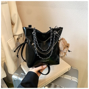 Détail du sac seau en cuir noir brillant avec chaîne argentée et breloque ours en peluche