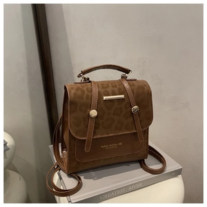 Detail view of leopard print backpack with brown leather straps and gold metal hardware