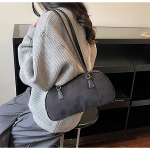 Detail of minimalist black suede shoulder bag with dual straps worn by a model