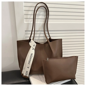Detail of dark brown tote bag with matching pouch and fashion ribbon on black bench
