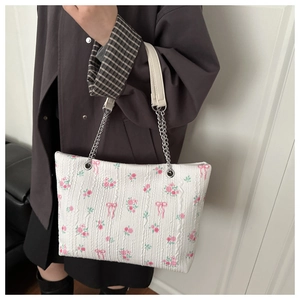 Close-up of floral tote bag with pink blossoms and elegant silver chain handle strap