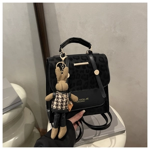 Detail of leopard print handbag featuring a gold bar accent and a bunny doll pendant