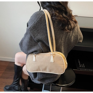 Detailed view of light brown suede shoulder bag with white leather contrast piping