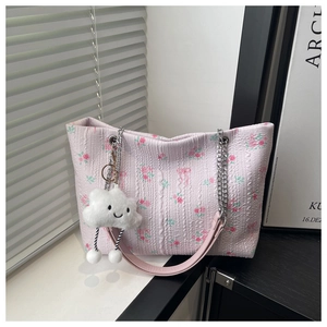 Detailed texture of pink floral tote bag with silver chain handle and cloud plush charm