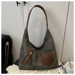 Detail of dark grey canvas tote bag with brown leather accents and exterior zip pockets