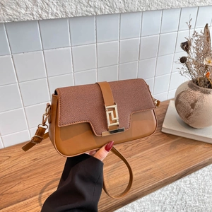 Sac bandoulière marron avec texture tissée et boucle dorée sur fond de carreaux blancs
