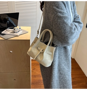 Elegant beige pleated crossbody bag with buckle detail shown in a lifestyle setting