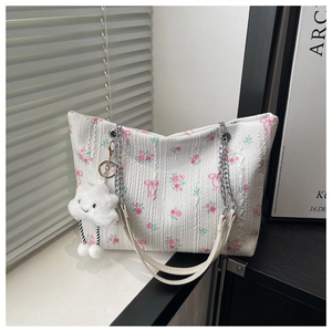 Close-up of floral tote bag with pink rose patterns and a cute plush cloud charm