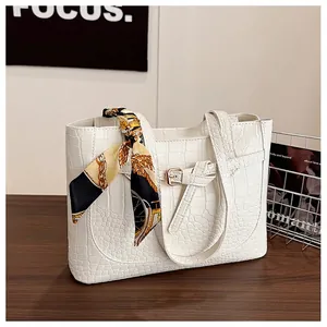 Close-up of white crocodile pattern tote bag with decorative silk scarf on handle