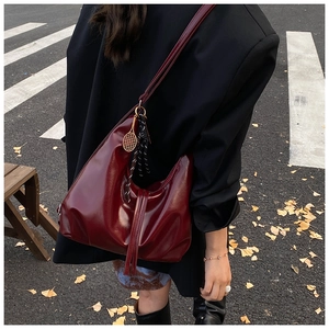 Detail of burgundy glossy Hobo bag with tennis racket charm and striped silk scarf