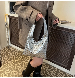 Détail du sac hobo argenté avec rivets métalliques et look urbain au fini brillant