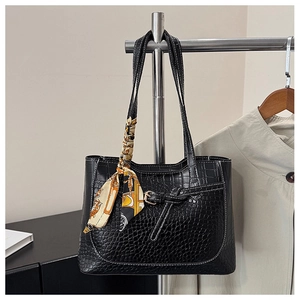 Detail of black crocodile texture tote bag featuring decorative scarf and buckle accent