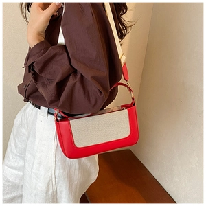 Detail of red leather and beige woven crossbody bag with adjustable wide strap on model