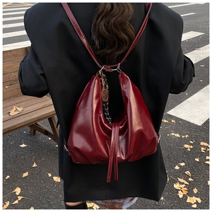 Detail of a deep red glossy tote bag featuring a vintage aesthetic and crumpled leather texture