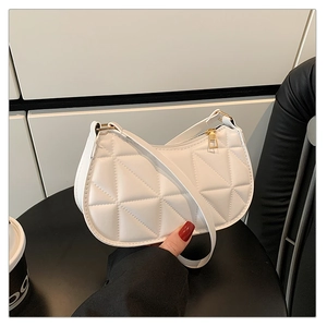 Detail of white quilted crescent bag with diamond pattern and golden zipper hardware
