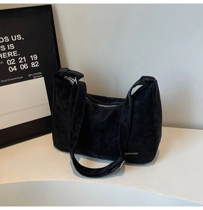Detail of matte suede texture and adjustable buckle on black hobo shoulder bag