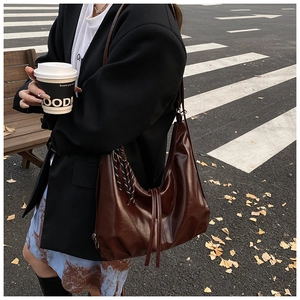 Close-up of vintage dark brown faux leather tote bag with stylish side braiding and drawstring