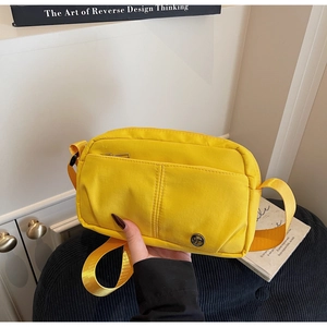 Detail view of the yellow crossbody bag with zipper pockets and adjustable strap