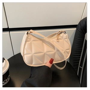 Close-up of off-white quilted handbag with triangular stitching and gold zipper details