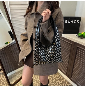 Détail du sac sous l'aisselle en cuir noir avec des clous argentés et forme en croissant