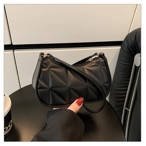 Detail of black underarm bag featuring geometric triangular quilted texture and sleek zipper