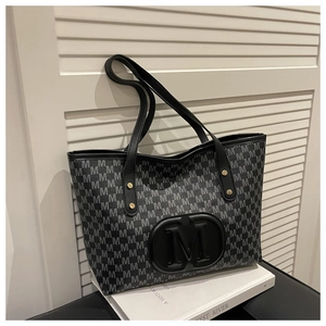 Detailed close-up of large embossed M logo and rivet accents on the printed tote bag