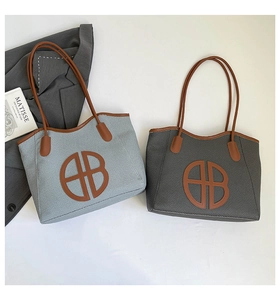 Detail view of large tote bags in grey with leather straps and circular logo design
