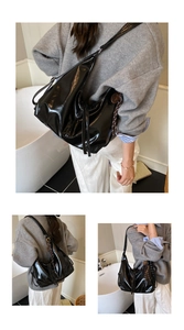 Detail of black glossy tote bag featuring drawstring tassels and adjustable shoulder strap