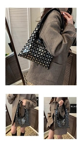 Vue détaillée du sac sous l'aisselle en cuir brillant noir avec des rivets argentés