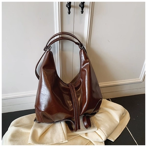 Detail of glossy brown leather tote bag with classic hobo curve and twin handles