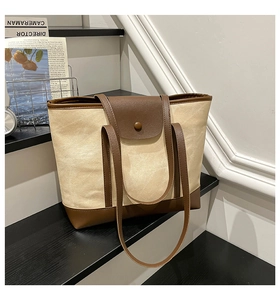 Detail of canvas tote bag with brown leather trim and retro metal snap button closure
