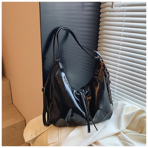 Detail of vintage black oil wax leather hobo bag with a tennis racket tassel pendant