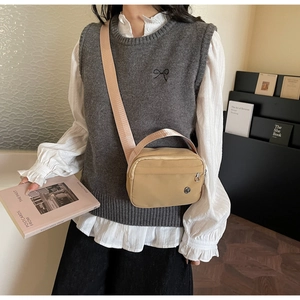 Detail of khaki nylon crossbody bag with wide pink strap and round metal logo