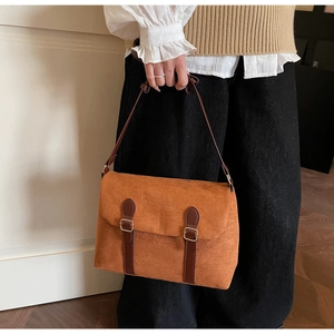 Detailed close-up of retro suede shoulder bag with dark leather straps and metal buckles