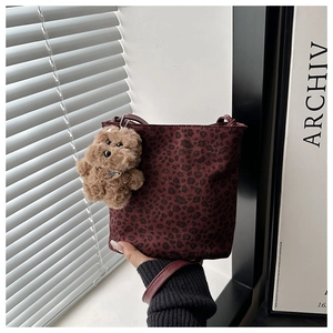 Close-up of leopard print bucket bag in burgundy suede with plush puppy charm detail